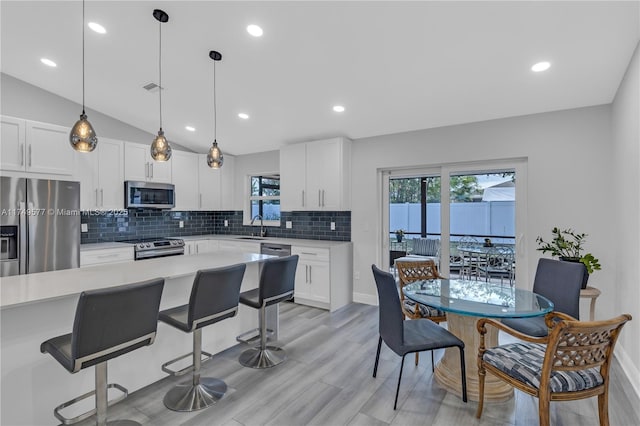 kitchen with stainless steel appliances, light countertops, decorative light fixtures, and white cabinets