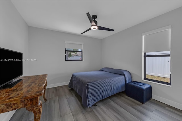 bedroom with light wood-style floors, a ceiling fan, and baseboards