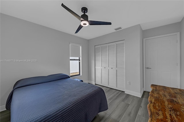 bedroom featuring wood finished floors, a ceiling fan, visible vents, baseboards, and a closet