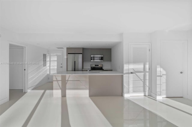 kitchen with a breakfast bar, a sink, light countertops, appliances with stainless steel finishes, and modern cabinets