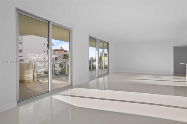 spare room featuring a wall of windows and tile patterned floors