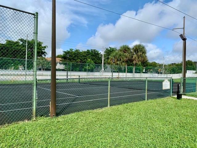 view of tennis court with fence and a lawn