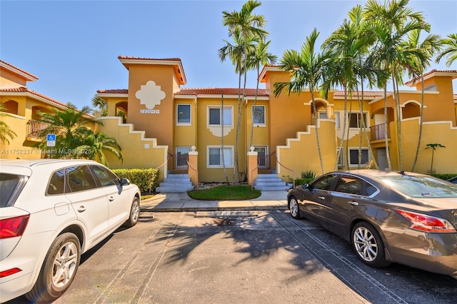 view of front of home with uncovered parking, a tiled roof, and stucco siding