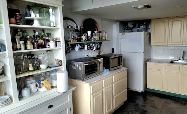 kitchen featuring a sink, visible vents, freestanding refrigerator, open shelves, and stainless steel microwave