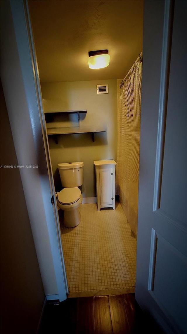 bathroom with toilet, visible vents, and tile patterned floors