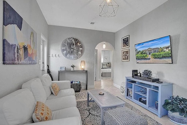 living area with arched walkways, baseboards, and tile patterned floors