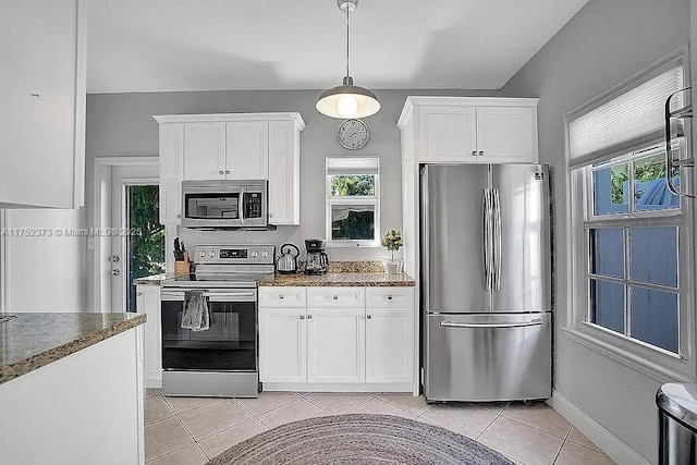 kitchen with a healthy amount of sunlight, light tile patterned floors, appliances with stainless steel finishes, and white cabinets