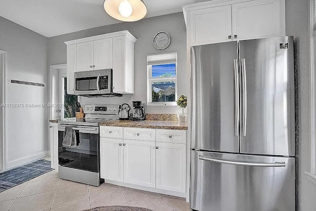 kitchen featuring light tile patterned floors, stainless steel appliances, stone countertops, white cabinets, and baseboards