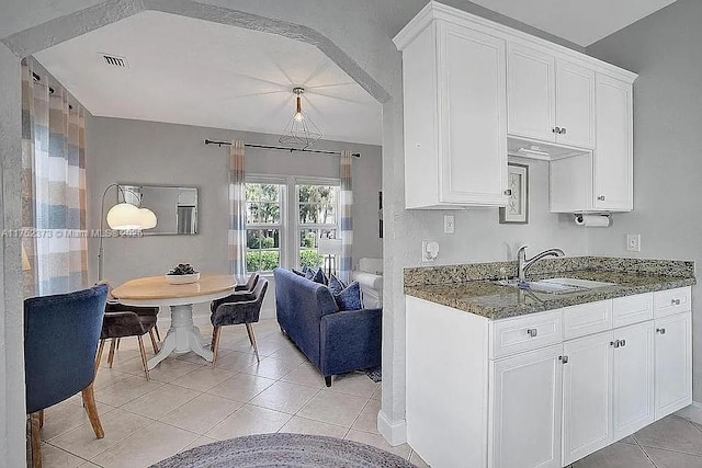 kitchen featuring white cabinets, a sink, decorative light fixtures, and light tile patterned floors