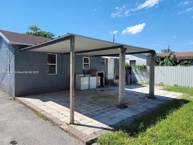 view of patio / terrace with a carport, washing machine and dryer, and fence