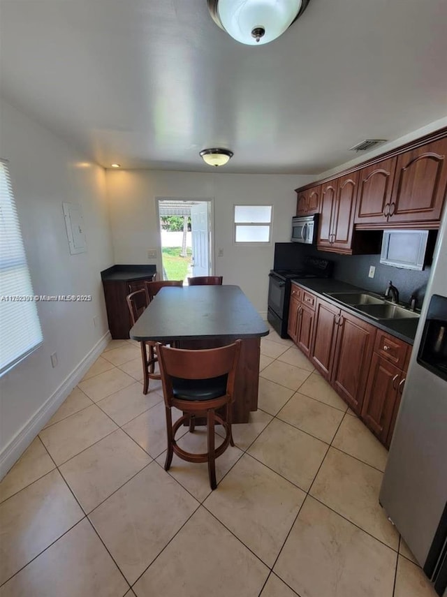 kitchen with dark countertops, black electric range oven, stainless steel microwave, and a sink