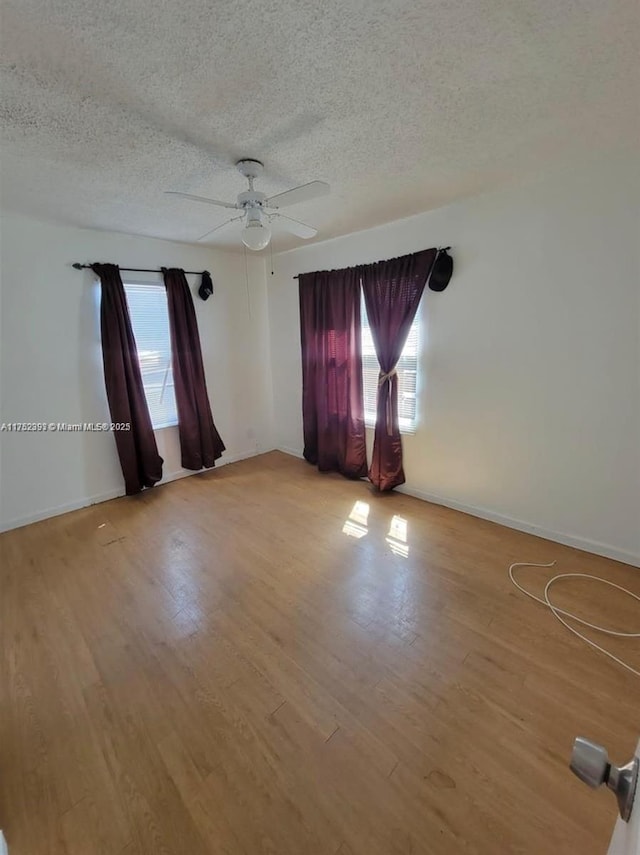 unfurnished room featuring light wood-style flooring, a textured ceiling, a ceiling fan, and a wealth of natural light