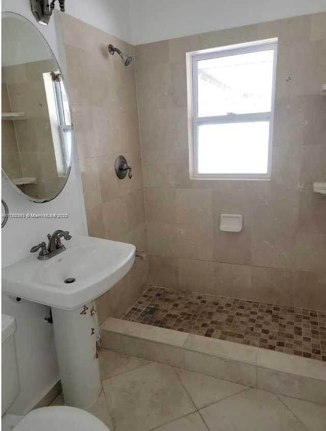 bathroom featuring tile patterned flooring, a tile shower, and toilet