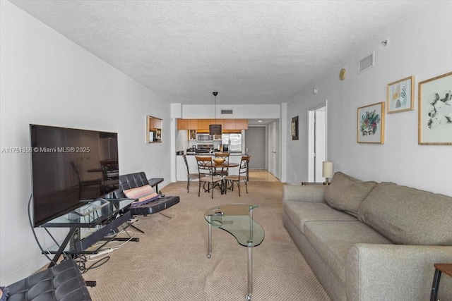 living room with visible vents, light carpet, and a textured ceiling