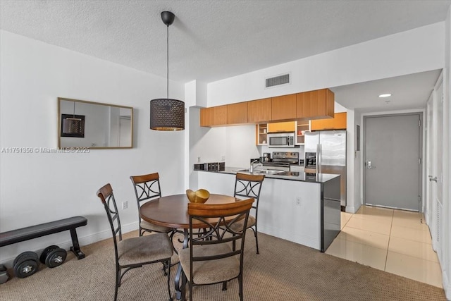 dining space with a textured ceiling, light tile patterned floors, visible vents, and baseboards