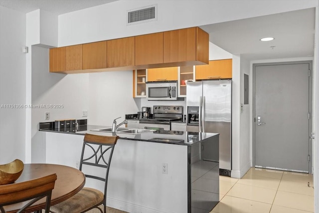 kitchen featuring a peninsula, a sink, visible vents, appliances with stainless steel finishes, and dark countertops