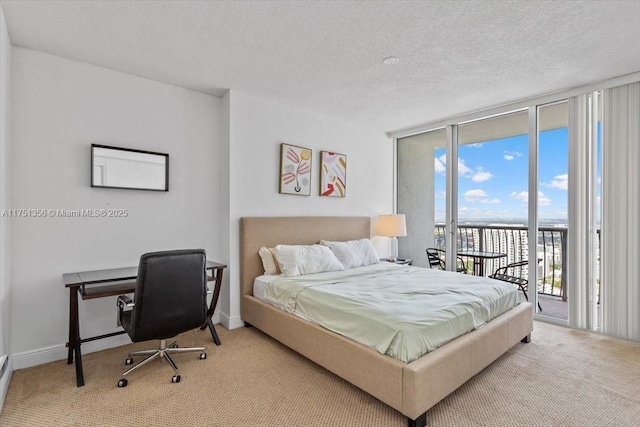 bedroom with expansive windows, access to outside, a textured ceiling, and light carpet