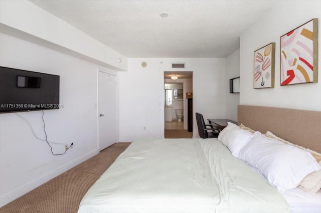 bedroom featuring baseboards, visible vents, light colored carpet, ensuite bath, and a textured ceiling