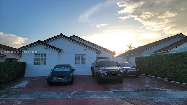 property exterior at dusk with a tiled roof and stucco siding