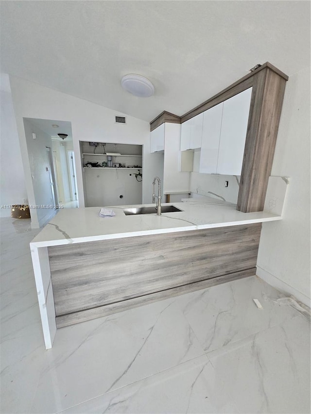 kitchen with white cabinets, modern cabinets, marble finish floor, light countertops, and a sink