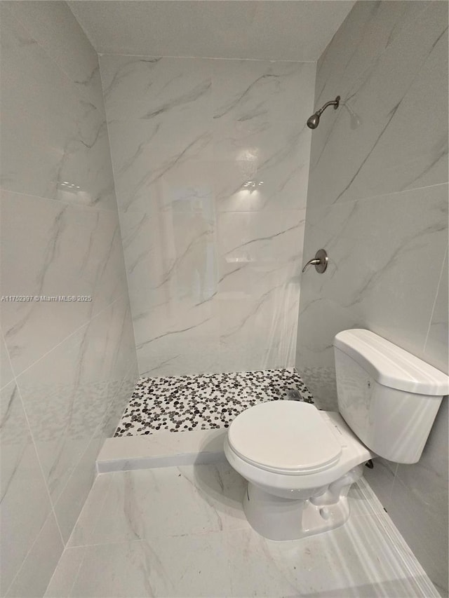 bathroom with toilet, marble finish floor, a marble finish shower, and tile walls