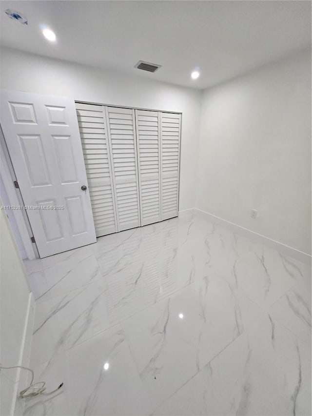 unfurnished bedroom featuring marble finish floor, baseboards, a closet, and recessed lighting