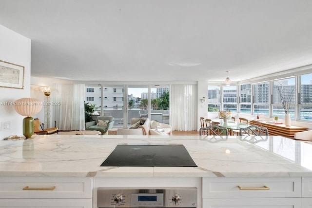 kitchen with open floor plan, white cabinetry, black electric cooktop, and light stone countertops