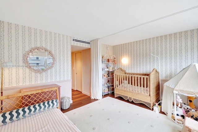 bedroom featuring wallpapered walls and wood finished floors