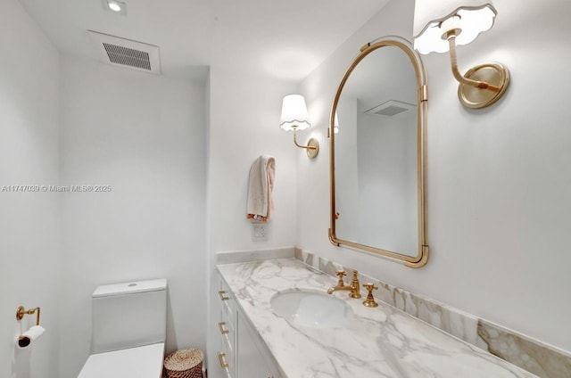 half bathroom featuring toilet, vanity, and visible vents