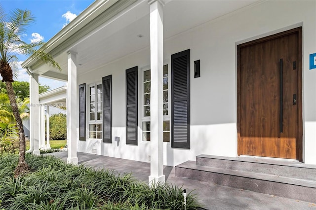 doorway to property with covered porch and stucco siding