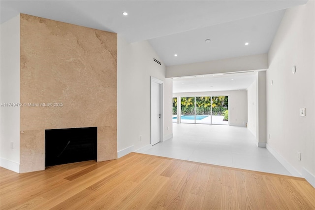 unfurnished living room with a premium fireplace, recessed lighting, wood finished floors, and baseboards