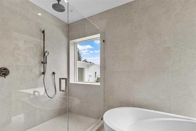 bathroom with a freestanding tub, walk in shower, and tile walls