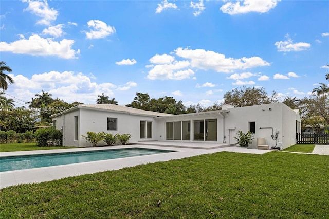 back of property with a yard, an outdoor pool, a patio, and stucco siding