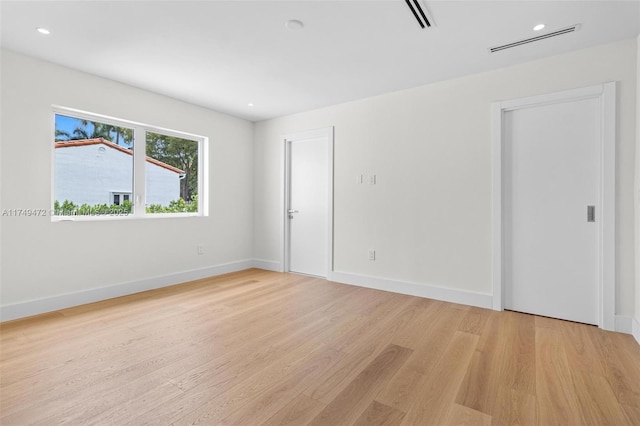 spare room featuring light wood-style flooring, visible vents, baseboards, and recessed lighting