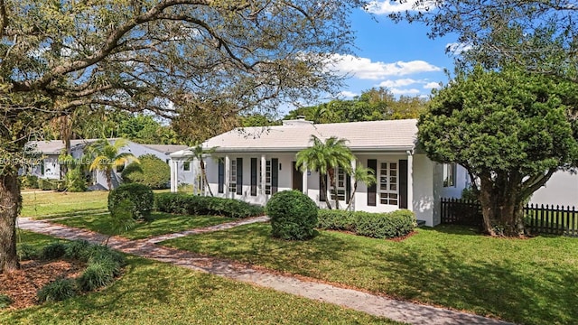 view of front facade featuring a tile roof, fence, a front lawn, and stucco siding