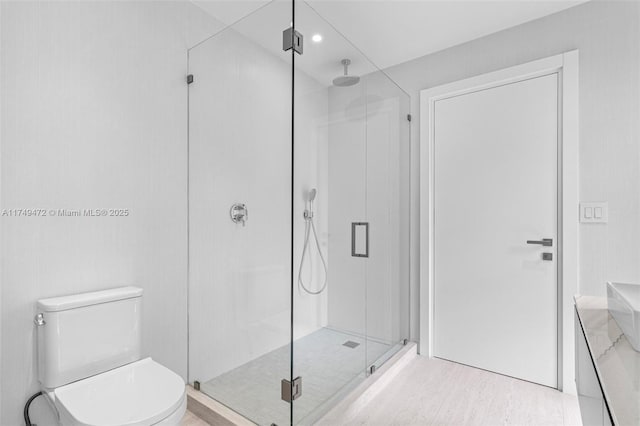 bathroom with a shower stall, toilet, and wood finished floors