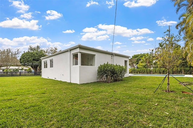 view of side of property featuring a yard, fence, and stucco siding