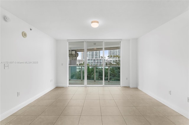 unfurnished room with light tile patterned floors, baseboards, and a wall of windows