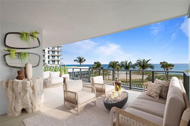 balcony with an outdoor living space with a fire pit and a water view