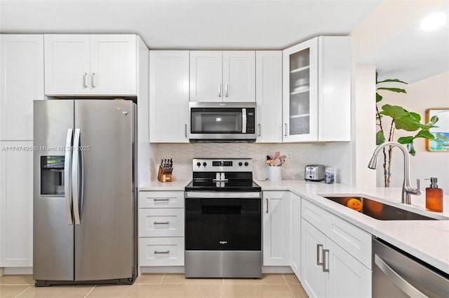 kitchen featuring stainless steel appliances, a sink, glass insert cabinets, and white cabinetry