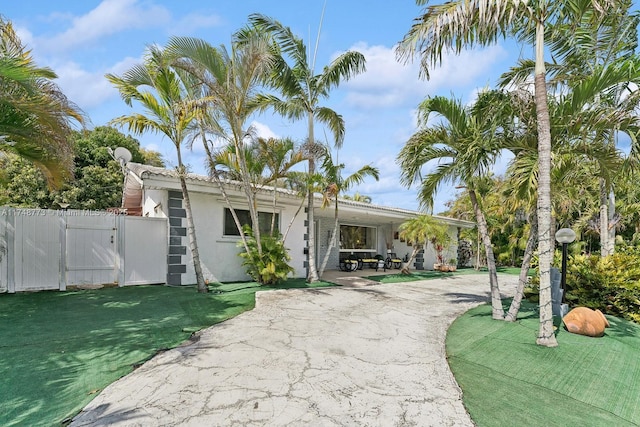 view of front facade featuring stucco siding, a gate, fence, a patio area, and a front yard