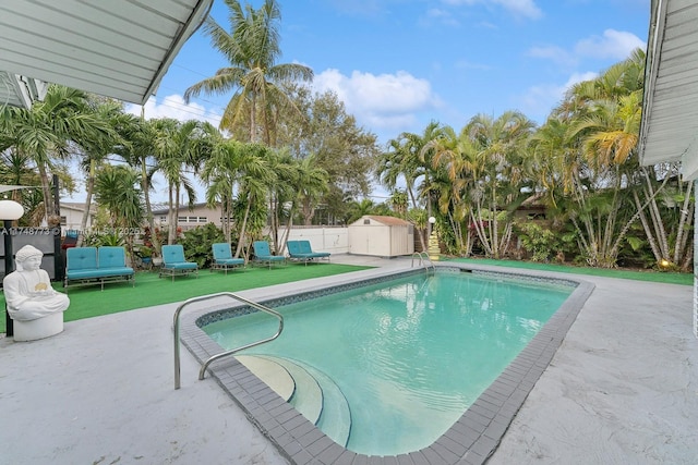 view of pool featuring a patio, a fenced backyard, an outdoor structure, a fenced in pool, and a shed