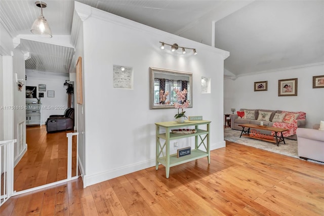 hallway with ornamental molding, light wood-type flooring, visible vents, and baseboards