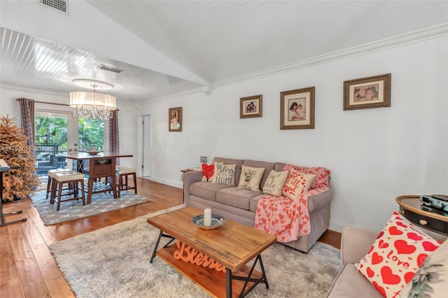 living area featuring visible vents, hardwood / wood-style floors, an inviting chandelier, ornamental molding, and baseboards