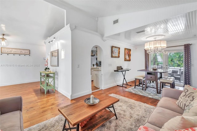 living area featuring arched walkways, hardwood / wood-style flooring, visible vents, and baseboards