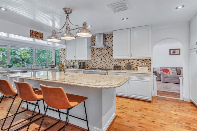 kitchen with visible vents, stainless steel dishwasher, range, wall chimney exhaust hood, and tasteful backsplash