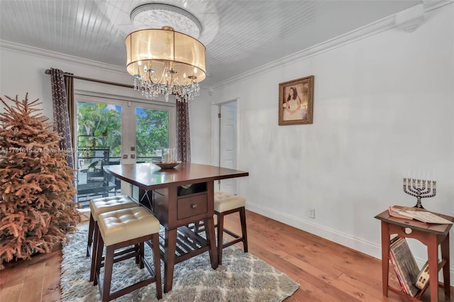 dining room with baseboards, ornamental molding, hardwood / wood-style floors, french doors, and a chandelier