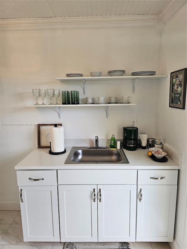 bar with marble finish floor, ornamental molding, and a sink