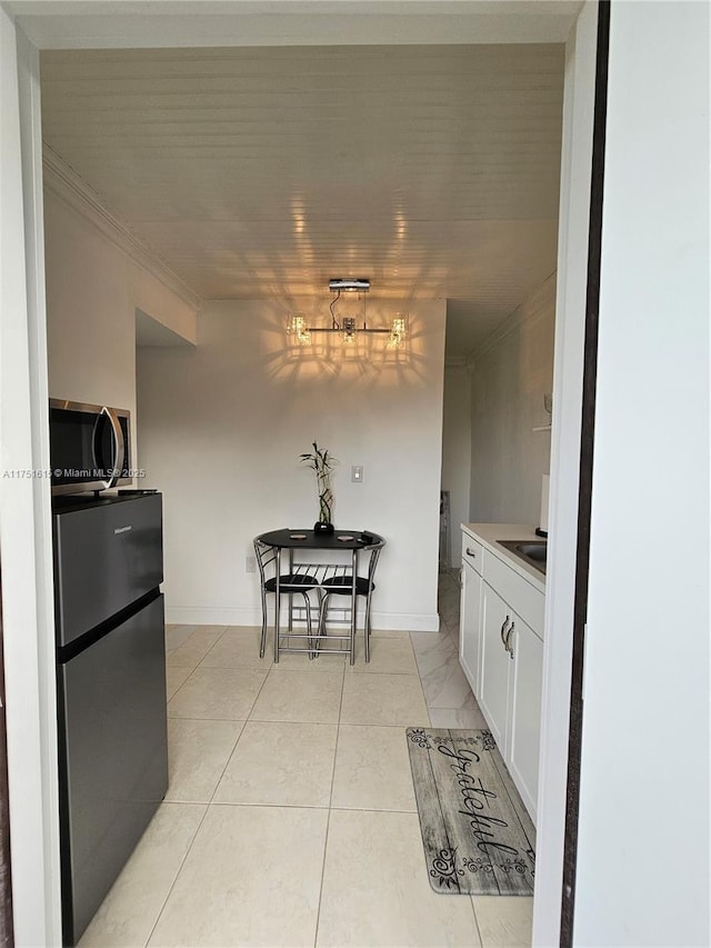 kitchen featuring crown molding, stainless steel appliances, light countertops, white cabinets, and baseboards