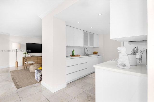 kitchen featuring a sink, white cabinetry, light countertops, modern cabinets, and glass insert cabinets